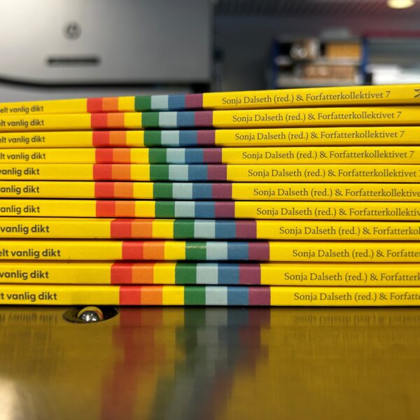EN bunke med bøker med mykt omslag, gul rygg, regnbueflagget på siden.